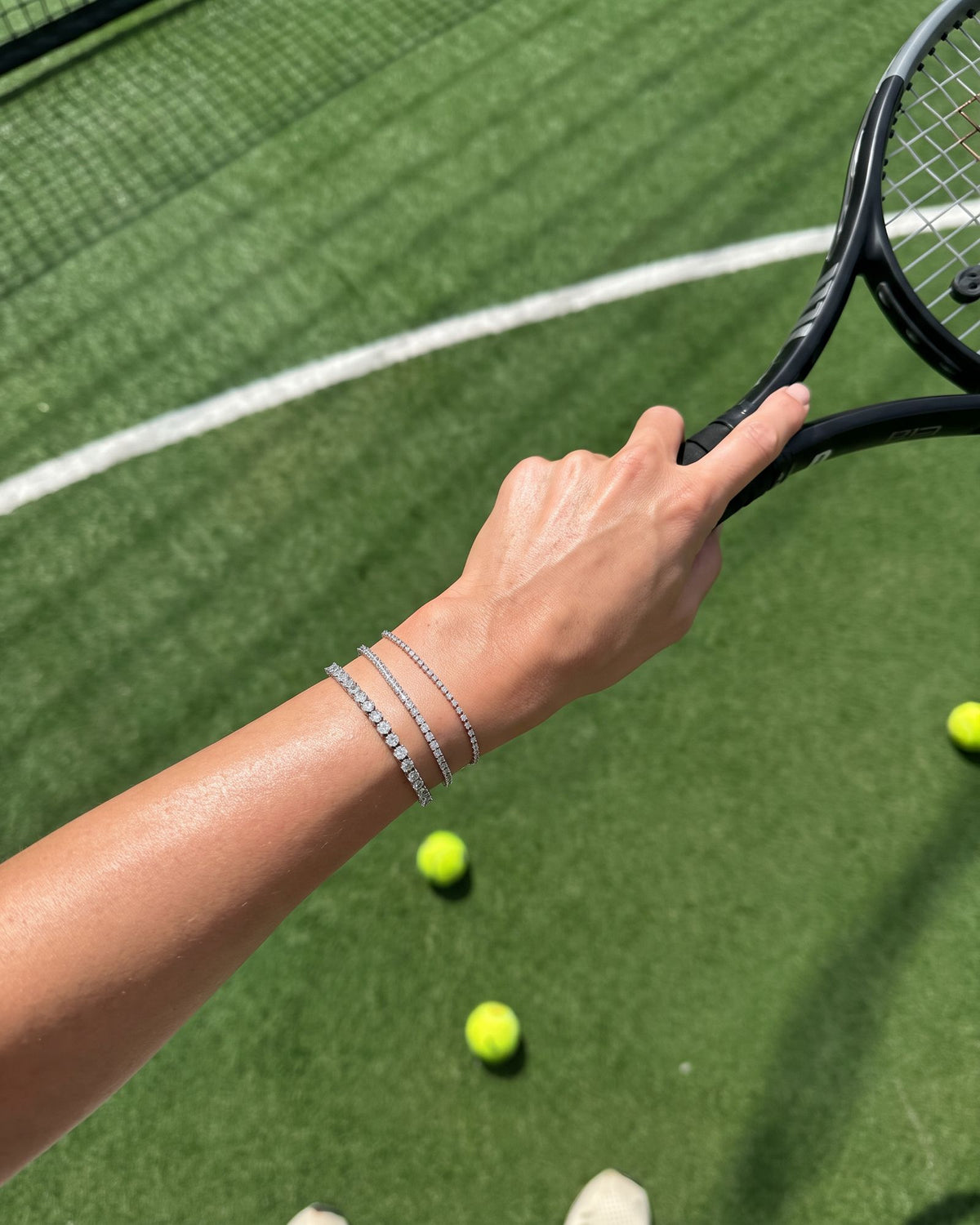 Moissanite tennis bracelets stacked on the tennis court